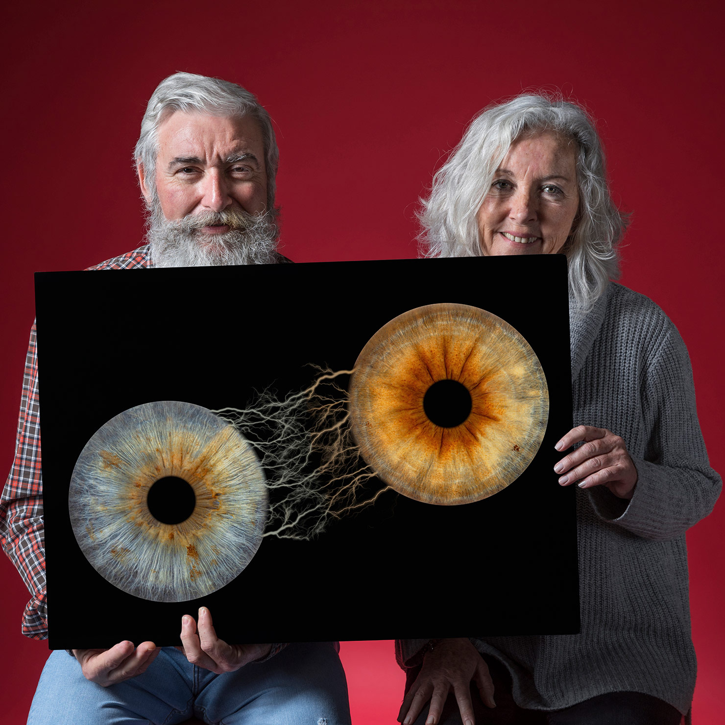 portrait-happy-senior-couple-holding-black-placard-looking-camera-against-red-background